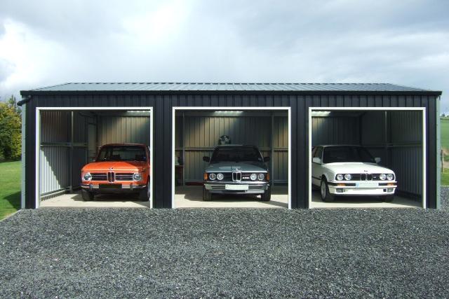 Three luxury old cars inside three bays of a building