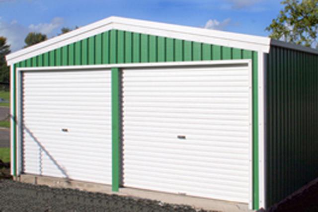 A green farm building with two white roller doors